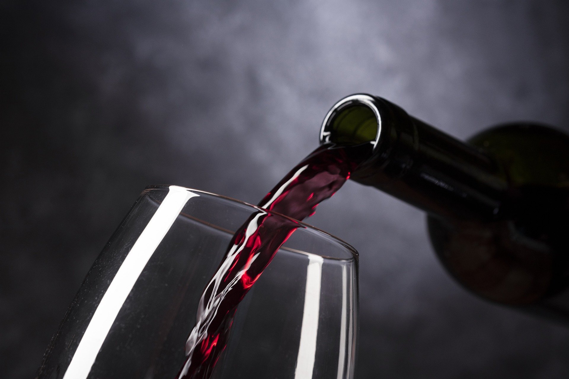 Rotwein wird in ein Weinglas eingeschenkt